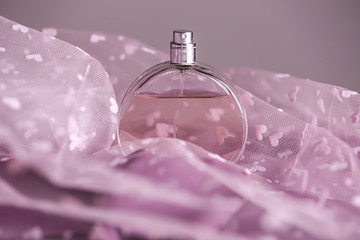 Bottle of perfume on color cloth, closeup