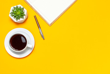 Obraz na płótnie Canvas Cup of coffee, open notebook with blank pages, pen, cactuses succulents on bright yellow minimalistic background top view Flat Lay with copy space. Still life, business, office, education concept