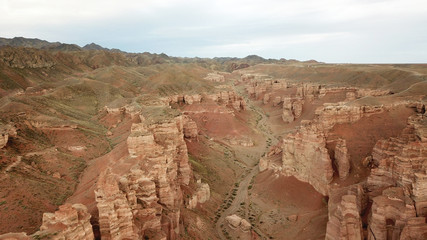 Charyn canyon. Grand canyon. Red sand and rocks. The sky in the clouds. Steep cliffs of the canyon. Shooting with the drone. Unusual footage. Clay rock canyon. Earth layers and different colors of roc - Powered by Adobe