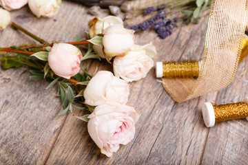 Flowers, tools, ribbons, roses, lavender, herbs, greens on the florist's table in flowershop. Wooden rustic style table, work space