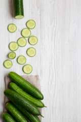 Fresh raw organic green cucumbers over white wooden surface, top view. Flat lay, from above, overhead. Space for text.