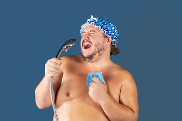 Funny fat man in blue cap sing in the shower