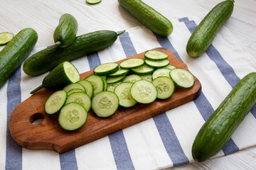 Chopped raw organic green cucumbers on rustic wooden board, side view. Closeup.