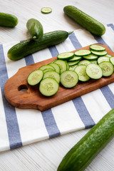 Chopped raw organic green cucumbers on rustic wooden board, side view. Close-up.