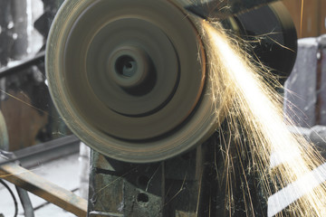 Electric grinder. A man working with electric grinder tool on steel structure in factory, sparks flying