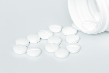 White prescription pills and bottle on white background.