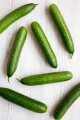 Fresh organic green cucumbers on white wooden background, top view. Flat lay, from above, overhead.