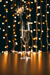Champagne with Christmas sparkle on garland light background