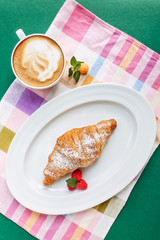 Latte art coffee with croissant so delicious on colorful napkin. Top view with copy space