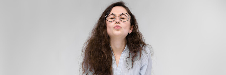 Obraz premium Young brunette girl with glasses. The girl pulls her lips for a kiss. The girl closed her eyes.
