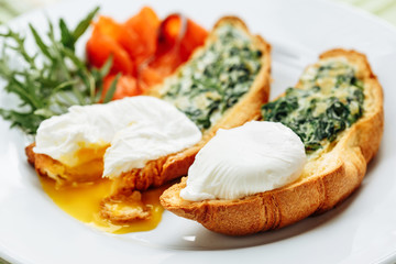Poached egg on whole wheat toasted croissant with arugula, smoked salmon. Table arrengement side close-up view copy space