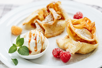 Crepes Pancakes with fruit jam and ice cream. Close-up side view on white wooden table