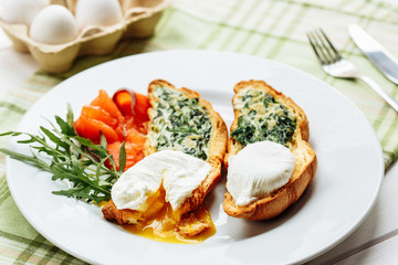Poached egg on whole wheat toasted croissant with arugula, smoked salmon. Table arrengement side close-up view copy space
