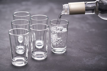 Vodka from the bottle is poured into a glass on a black background, selective focus