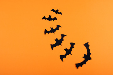 Flock of paper bats on orange wall.