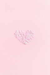 Heart made from star sequins on a pink pastel background