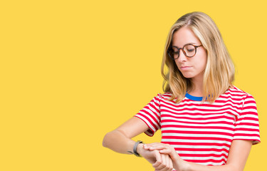 Beautiful young woman wearing glasses over isolated background Checking the time on wrist watch, relaxed and confident