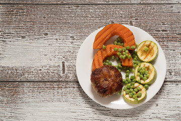 Grilled vegetables - tomatoes, asparagus, zucchini, bell pepper, pineapple slices and fresh cheese with fresh mint on cast iron black plate, gray slate background. Top view