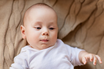 babyhood, childhood and people concept - sweet little baby boy lying on knitted blanket