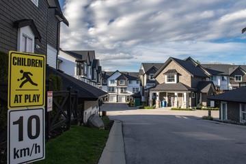Fototapeta premium Row of new residential townhouses on a street. Family townhouses with concrete driveways and asphalt road in front.