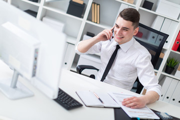 A young man sitting at a computer Desk in the office and looking at the monitor.