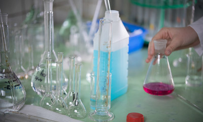 Table full of chemicals and flasks. Chemical lab. A hand touching a flask