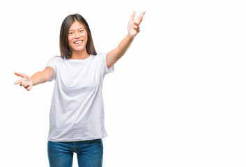 Young asian woman over isolated background looking at the camera smiling with open arms for hug. Cheerful expression embracing happiness.