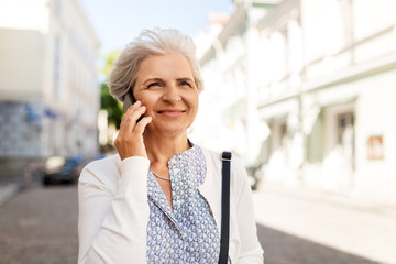 retirement, communication and old people concept - happy senior woman calling on smartphone in summer city