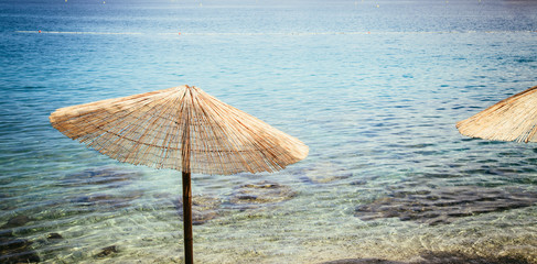 Paradiesischer Sommerurlaub: Sonnenliegen und Sonnenschirme, weißer Sandstrand und blaues Wasser...