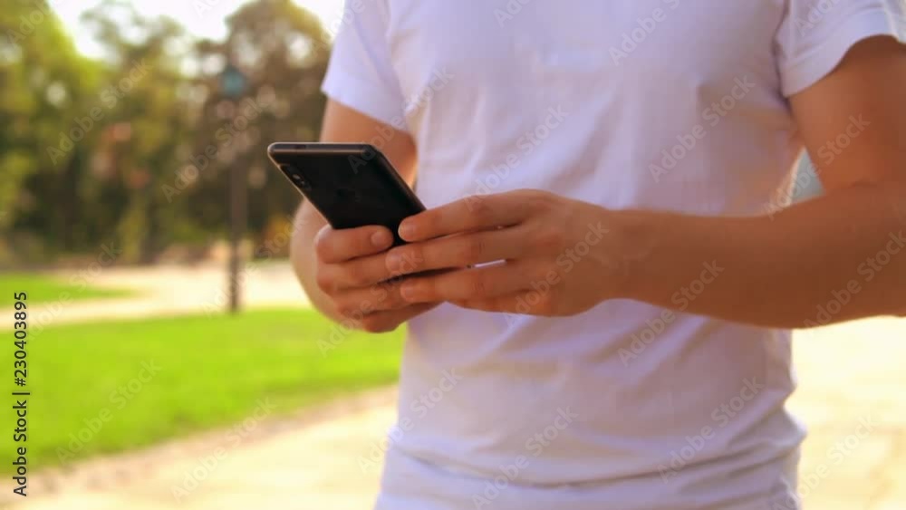 Poster close up details male hands using smartphone. man texting message or chatting on smart phone. walkin