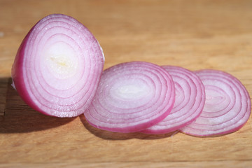 Red onion or Allium cepa half cut and sliced on a wooden cutting board