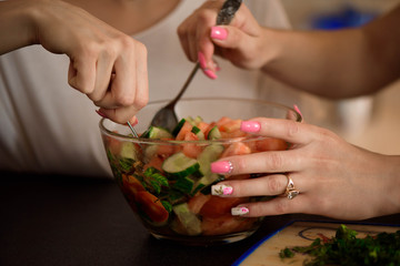 Young sisters making vegetable salad at home