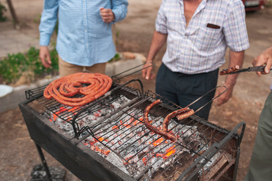 Group of farmers preparing red sausages in a barbecue at sunset, Lorca, Spain