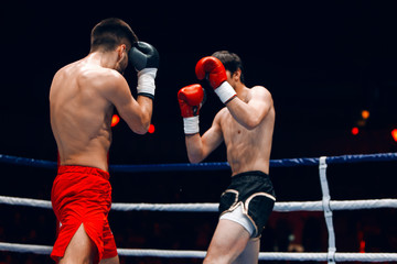 Fototapeta na wymiar Two professional boxers, athletes in dynamic boxing action on the ring under lights of sport arena