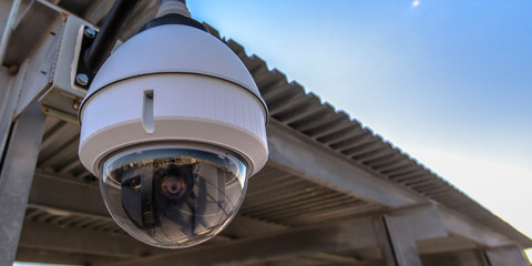 Fototapeta na wymiar White dome security camera overhanging on a roof