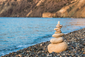 Fototapeta na wymiar concept photo balance - close-up of a pyramid of white stones on a pebble beach