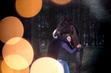 Frau umarmt Pferd im Wald
