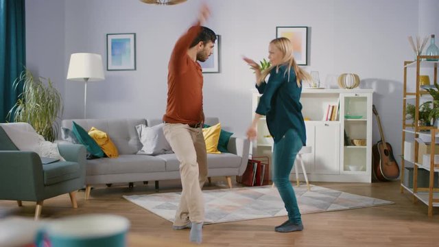 Beautiful Happy Young Couple in Love Dancing in the Middle of the Living Room. Boyfriend and Girlfriend Cheerfully Celebrate by Dancing at Home.