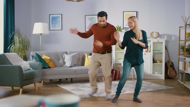 Beautiful Happy Young Couple in Love Dancing in the Middle of the Living Room. Boyfriend and Girlfriend Cheerfully Dance at Home.