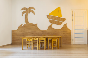 Cozy room with wooden table and chairs and decorative elements in wall in modern kindergarten
