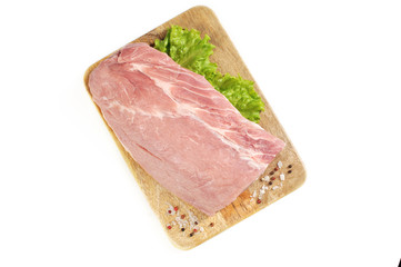 A piece of raw meat on a wooden board. A piece of pork carbonate for steaks. White background. Close-up. View from above. 