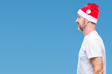 Middle age hoary senior man wearing christmas hat over isolated background looking to side, relax profile pose with natural face with confident smile.