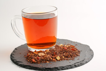 Still life, aromatic dry tea with fruits and petals, close up on with a cup of tea on white background, selective focus