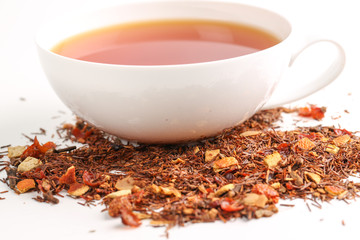 Still life, aromatic dry tea with fruits and petals, close up on with a cup of tea on white background, selective focus