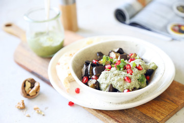 Roasted aubergines with pesto sauce decorated with pomegranate seeds.