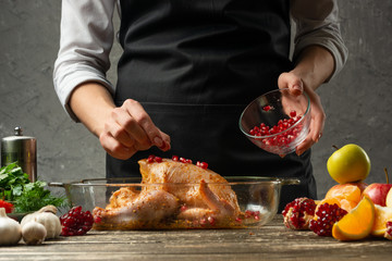 The chef prepares chicken with fruit for baking for a holiday, Christmas, New Year, on the background of a concrete wall. Background for the menu and for cooking recipes