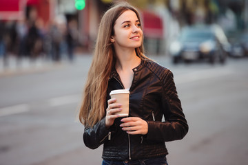 Fototapeta premium Beautiful woman holding paper coffee cup and enjoying a walk in the city
