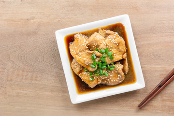 top view of pork with teriyaki sauce in a ceramic plate on wooden table. delicious and popular japanese food menu.