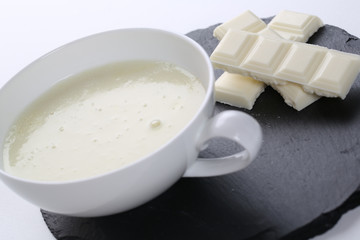 close up of cup of white hot chocolate on a white