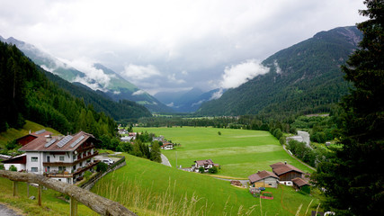 Fototapeta na wymiar Dunkle Wolken über dem Lechtal/Dunkle Wolken über den Bergen des Oberen Lechtales in Tirol, Oesterreich; Häuser in grünen Wiesen